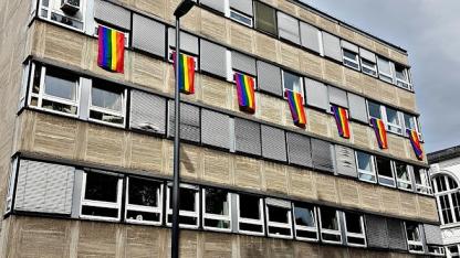 Außenfassade der Geschäftstelle mit Regenbogenflaggen an den Fenstern