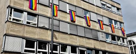 Außenfassade der Geschäftstelle mit Regenbogenflaggen an den Fenstern